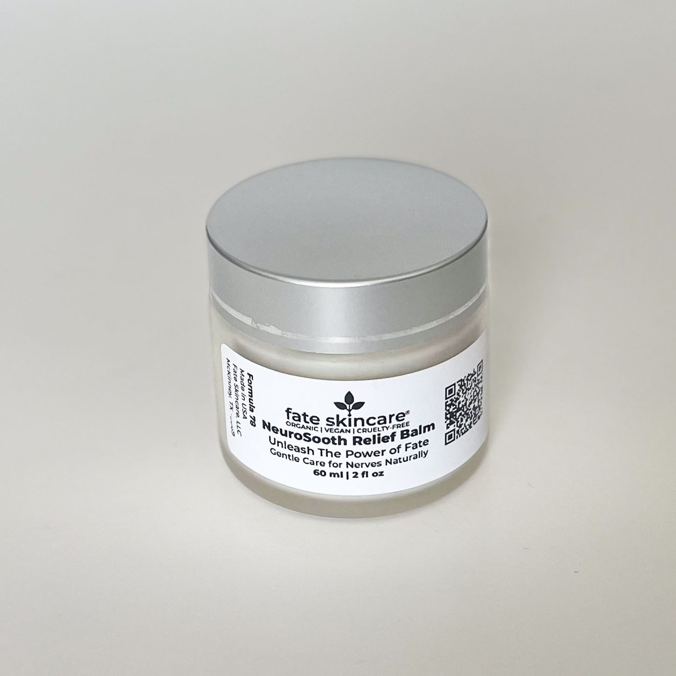 Fate Skincare's NeuroSoothe Relief Balm in a frosted glass jar with a silver metal lid, featuring a rectangular label displaying the product name and company logo.