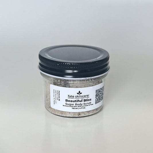 Fate Skincare's Beautiful Bliss Sugar Body Scrub in a clear glass jar with a black lid, featuring a round label displaying the product name and company logo.