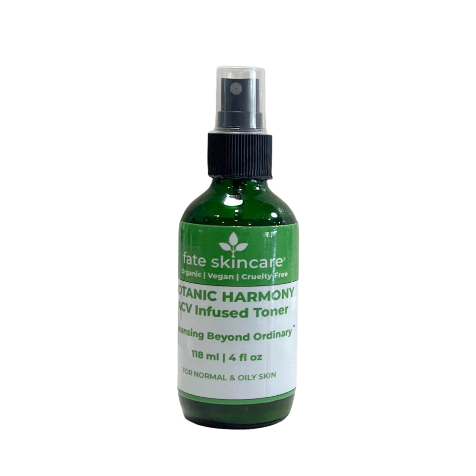 A green glass spray bottle of "Fate Skincare Botanic Harmony ACV Infused Toner" with a black spray nozzle, placed on a white surface with a textured white background. The label states that the toner is for normal and oily skin and describes it as "Cleansing Beyond Ordinary."