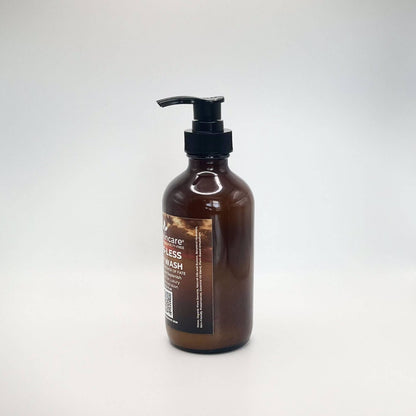 Fate Skincare's Suds-less Body Wash in a 8 ounce glass amber bottle equipped with a black pump dispenser. The label prominently displays the product's name in white extra-bold letters against a background of a golden sky.