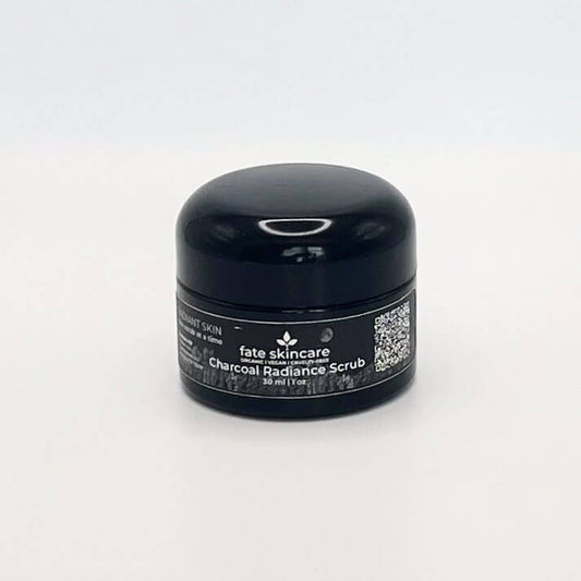 Black onyx glass container holding Fate Skincare's Charcoal Radiance Scrub, featuring Fate Skincare's iconic logo centered on a 1-ounce container.