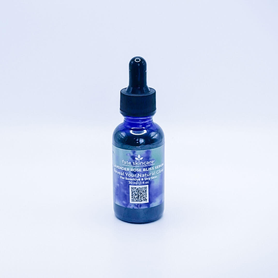 Fate Skincare's Lavender Rose Bliss Face Serum in a blue glass bottle with a black dropper, showcasing Fate Skincare's iconic logo on a subtle green nature-inspired background.