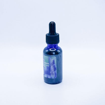 Fate Skincare's Lavender Rose Bliss Face Serum in a blue glass bottle with a black dropper, showcasing Fate Skincare's iconic logo on a subtle green nature-inspired background.