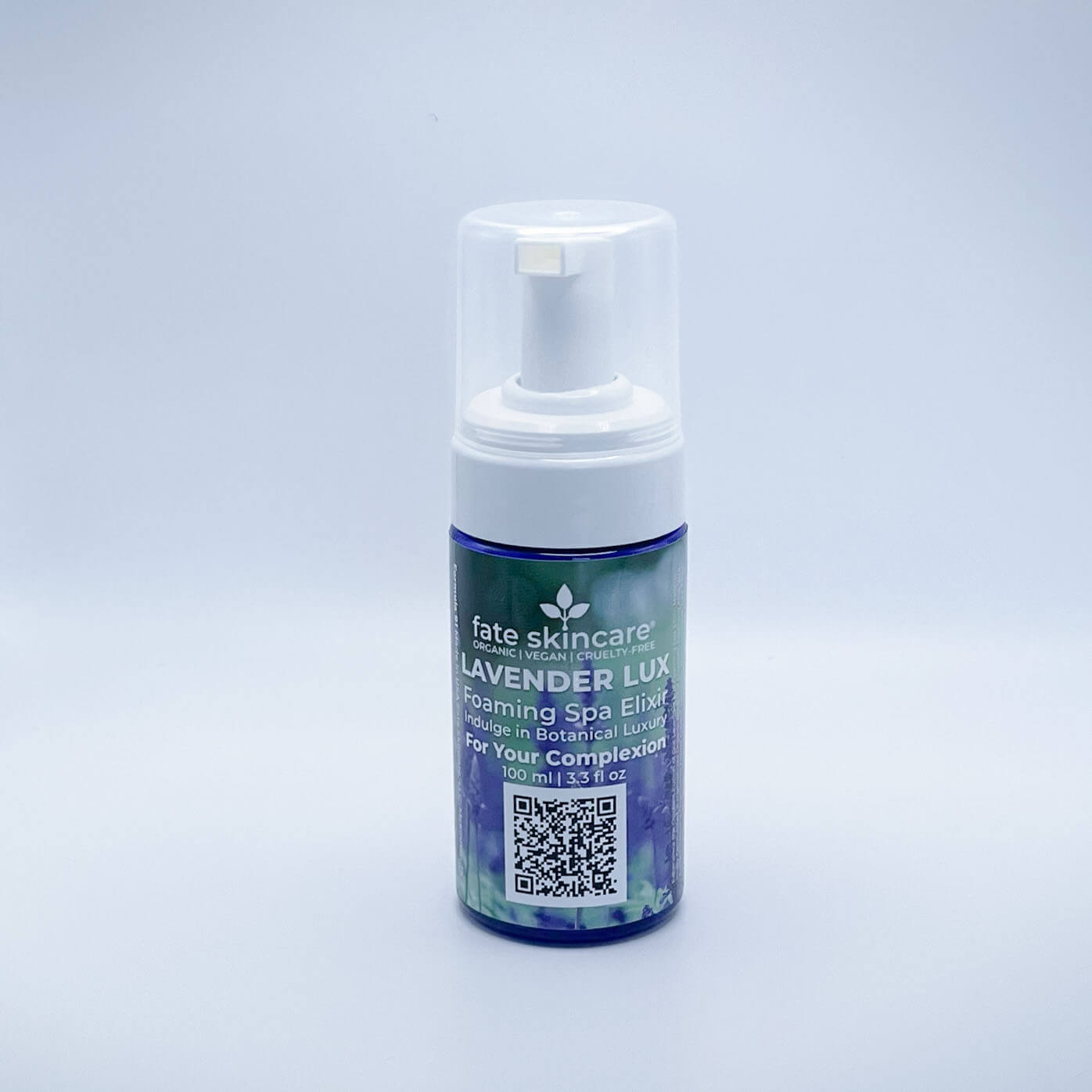 Fate Skincare's Lavender Lux Foaming Spa Elixir in a 3.3 fl. oz blue foaming dispenser with a white pump, featuring Fate Skincare's iconic logo on a subtle green nature-inspired background.